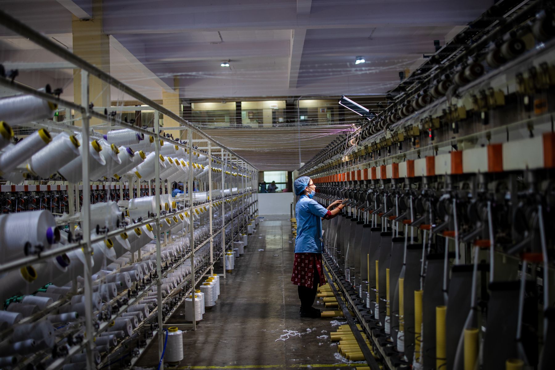 Operator checking textile production machinery