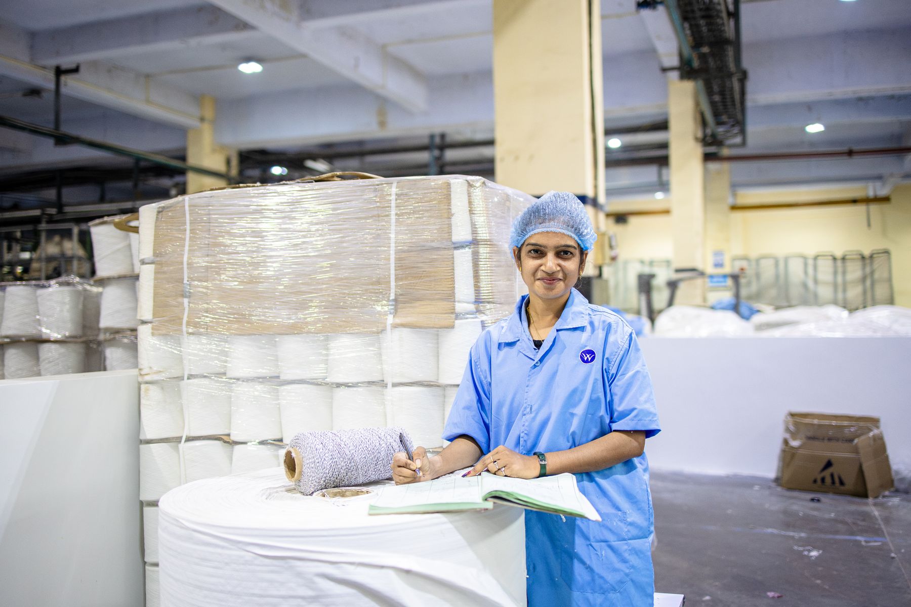 Operator recording observations beside packaged yarn